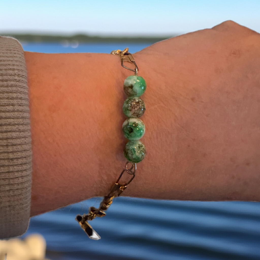 African Turquoise Glass Bead Bracelet worn on wrist, showcasing serene green and brown beads against a background of water.