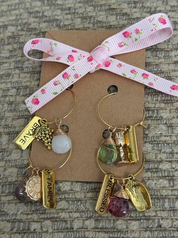 Handmade glass bottle charms featured on a gift card with floral ribbon and various gemstone accents.