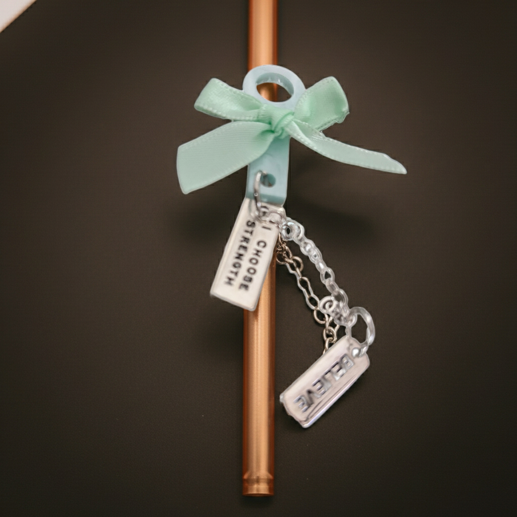 Copper straw with a mint green bow and charms on a dark background