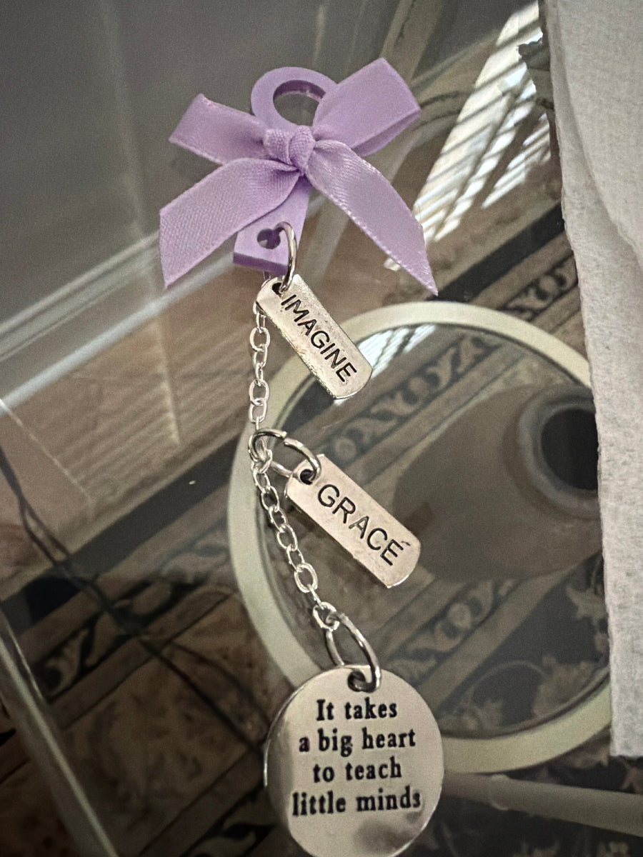 Bracelet with purple bow and engraved tags on a reflective surface