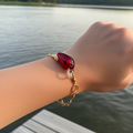 Fishing Lure Bracelet Red & Black worn on wrist by the lake, showcasing handcrafted design and metallic shimmer finish.
