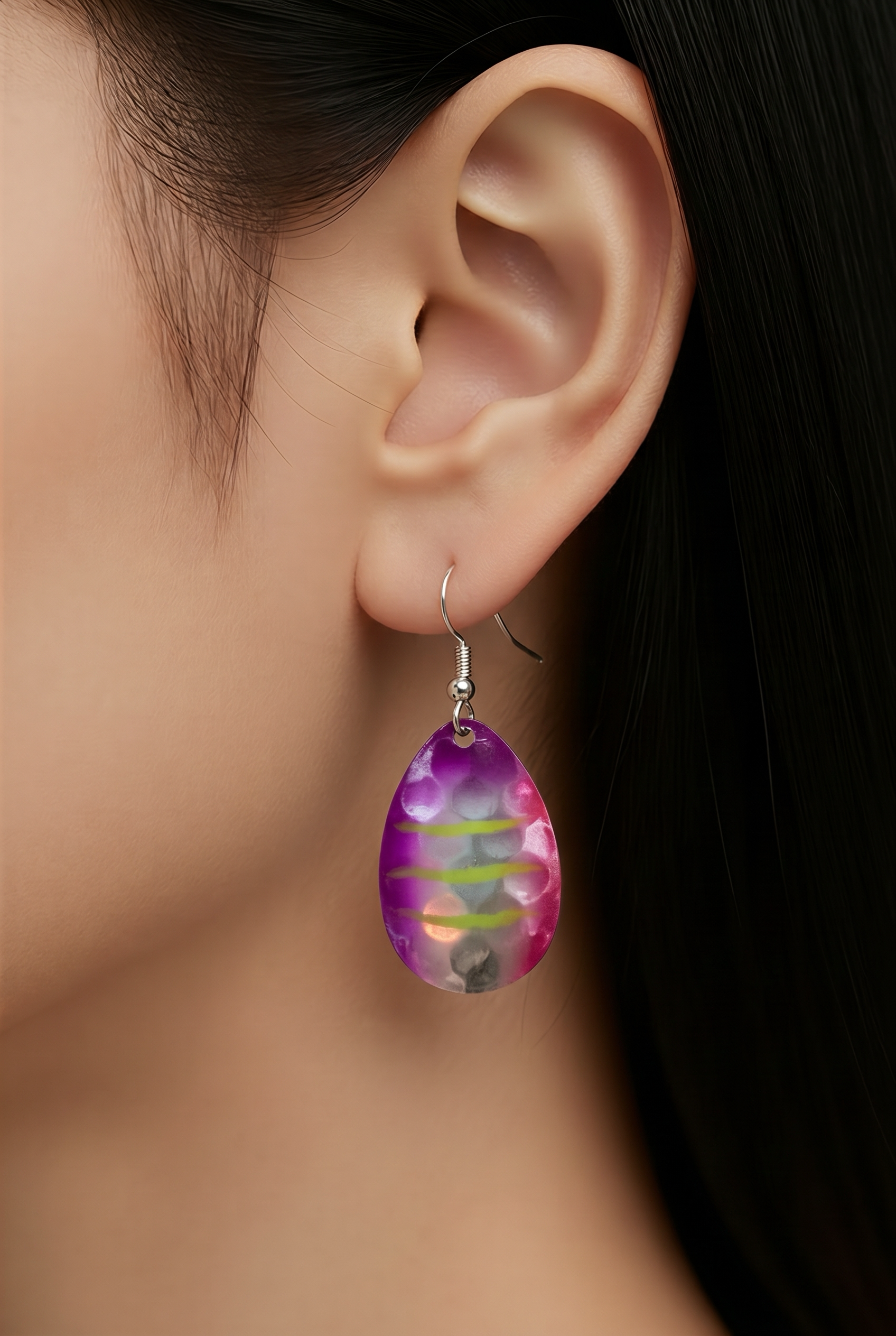 Close-up of a colorful teardrop earring worn by a person.