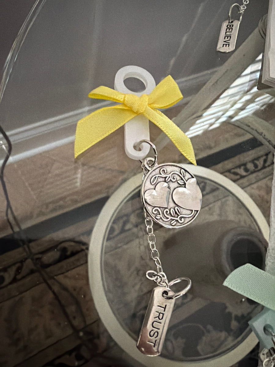 Decorative keychain with a yellow bow and 'Trust' tag on a blurred background